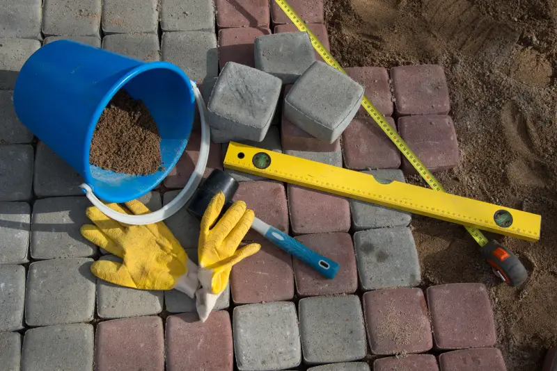 Concrete Work and Hardscaping_Pavers Pavement details stone blocks rubber hammer level gloves and tape measure